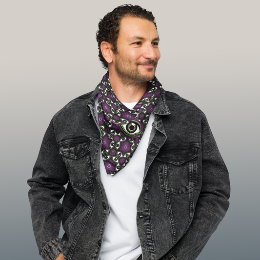 Handsome man wearing a purple bandana around his neck with a all-seeing eye pattern with green, white and black accents, the eye known for it's protective qualities throughout history.